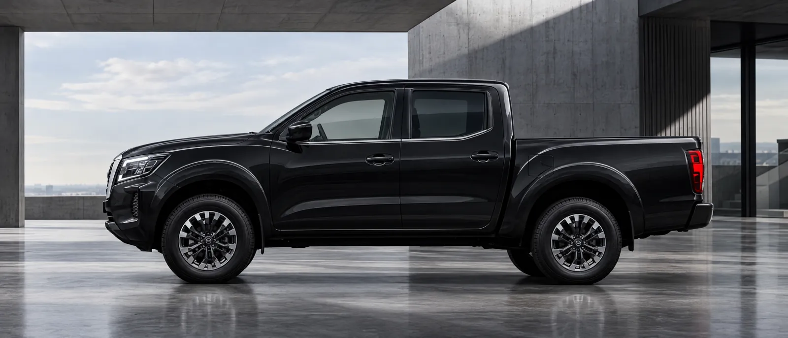 Nissan Frontier negra de perfil en un espacio de arquitectura industrial