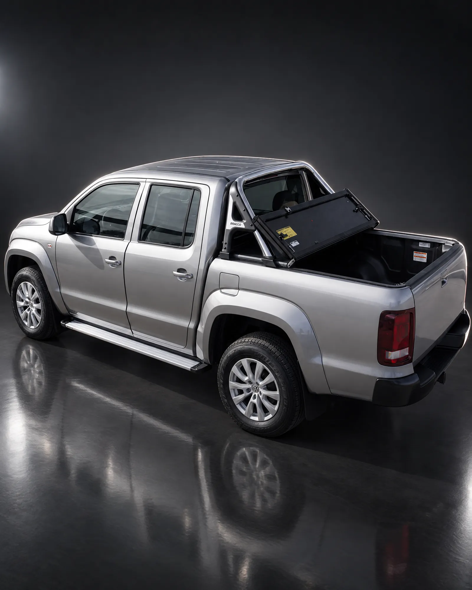 Volkswagen Amarok con tapa rígida rebatible Bracco abierta y jaula en estudio oscuro (referencia de la línea)